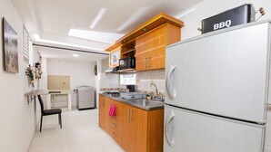 Eine kompakte Küche mit Holzschränken, einem Edelstahlkühlschrank, einer Mikrowelle und einem kleinen Spülbecken.