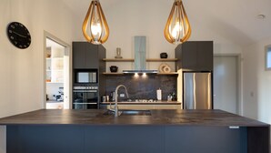 A modern kitchen with a central island, stainless steel appliances, and pendant lighting. - Beautiful 3 bedroom home | Hot Tub | Stunning View (Jacks Point)