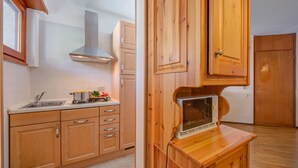 Una cucina con mobili in legno, un lavello in acciaio inossidabile e un forno a microonde integrato.