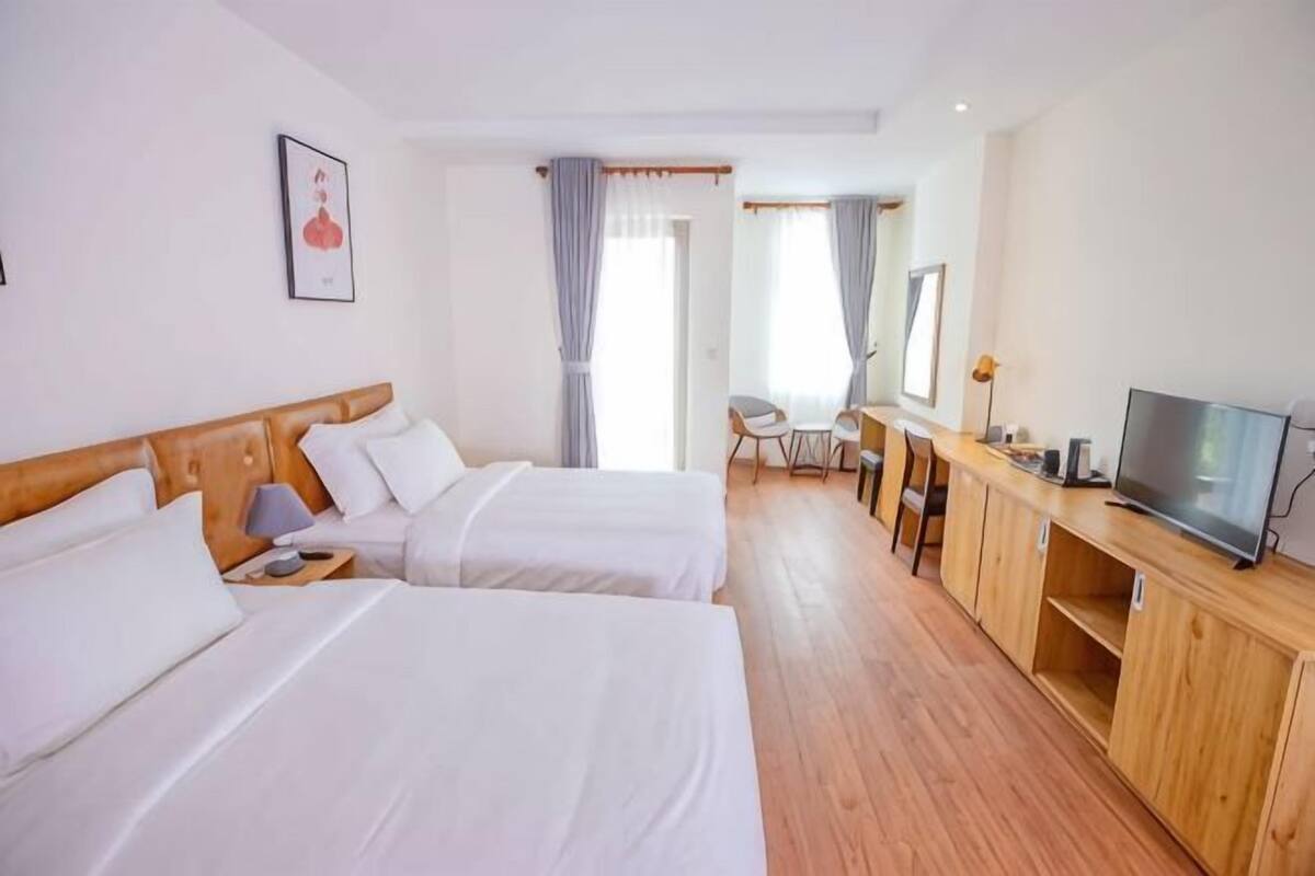 Een hotelkamer met twee bedden, een bureau met een televisie en een stoel.