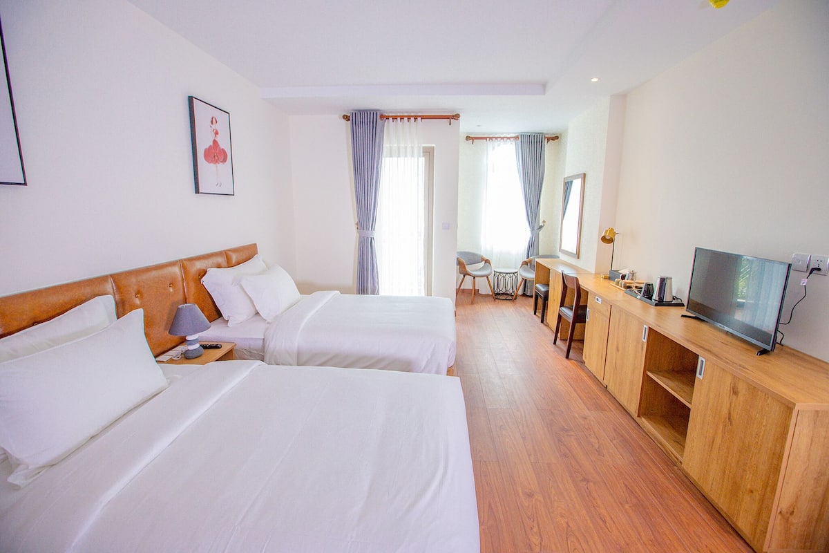 Een hotelkamer met twee bedden, een bureau met een televisie en een stoel.