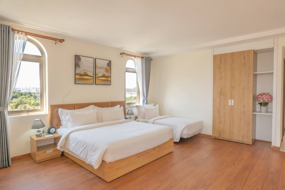 Een slaapkamer met twee bedden, een houten garderobe en een nachtkastje met een lamp.