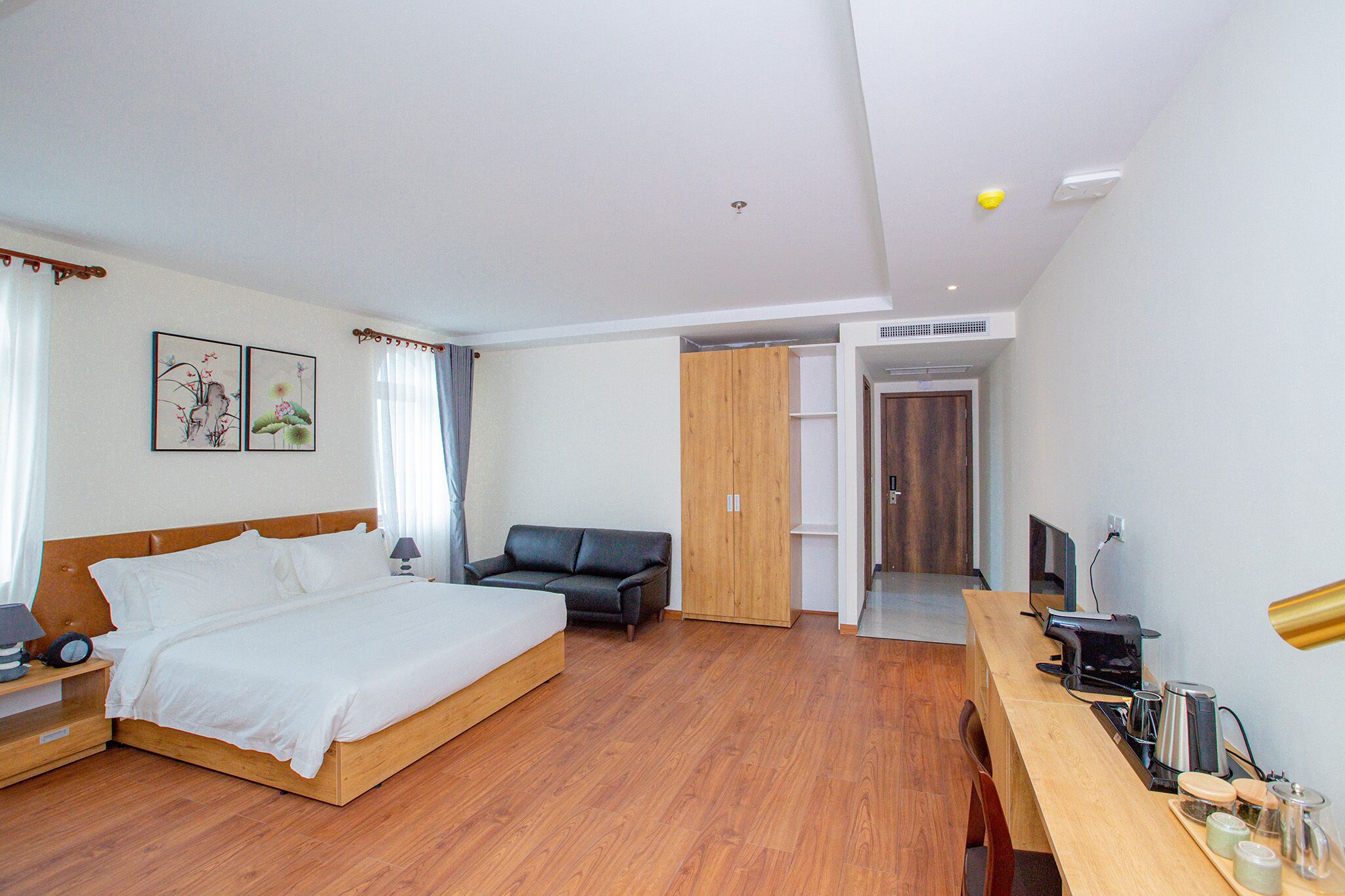 A hotel room with a bed, a desk with a computer, a chair, and a wardrobe.