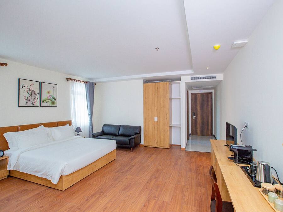 A hotel room with a bed, a desk with a computer, a chair, and a wardrobe.