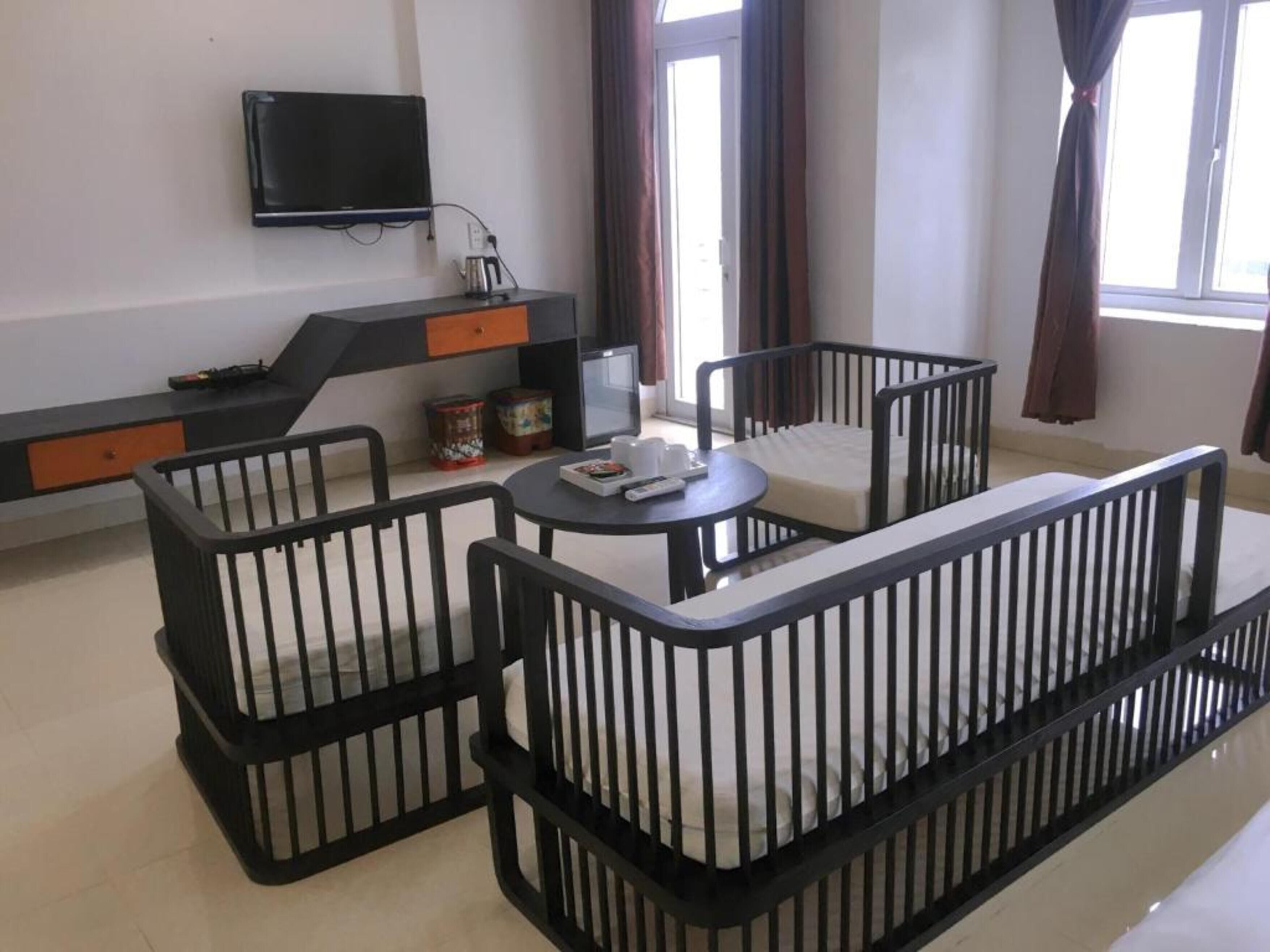 Una sala de estar moderna con una paleta de colores blanco y negro, que incluye un sofá, dos sillones, una mesita y un televisor montado en la pared.