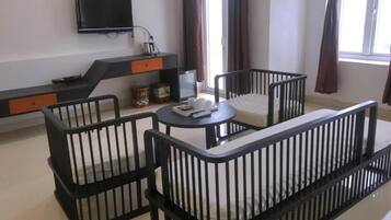 Una sala de estar moderna con una paleta de colores blanco y negro, que incluye un sofá, dos sillones, una mesita y un televisor montado en la pared.