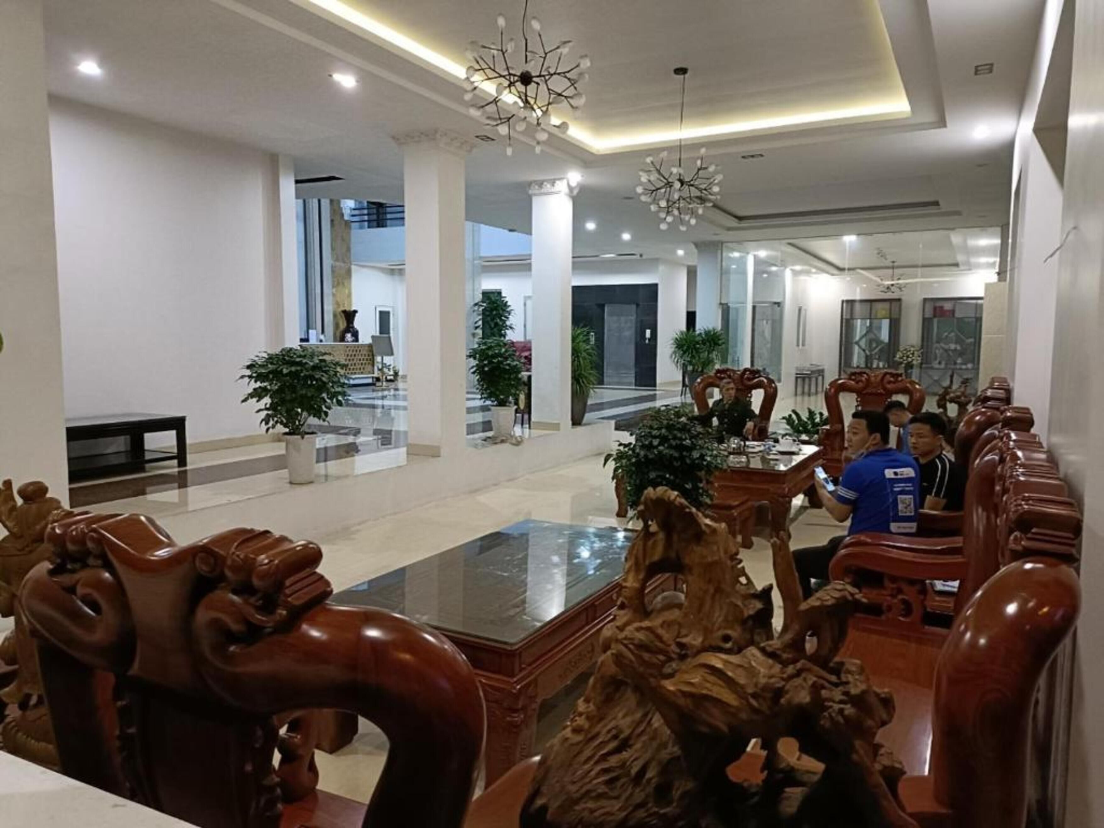 Un vestíbul ampli amb una llarga recepció, lluminàries modernes i una zona de seients amb cadires de fusta.