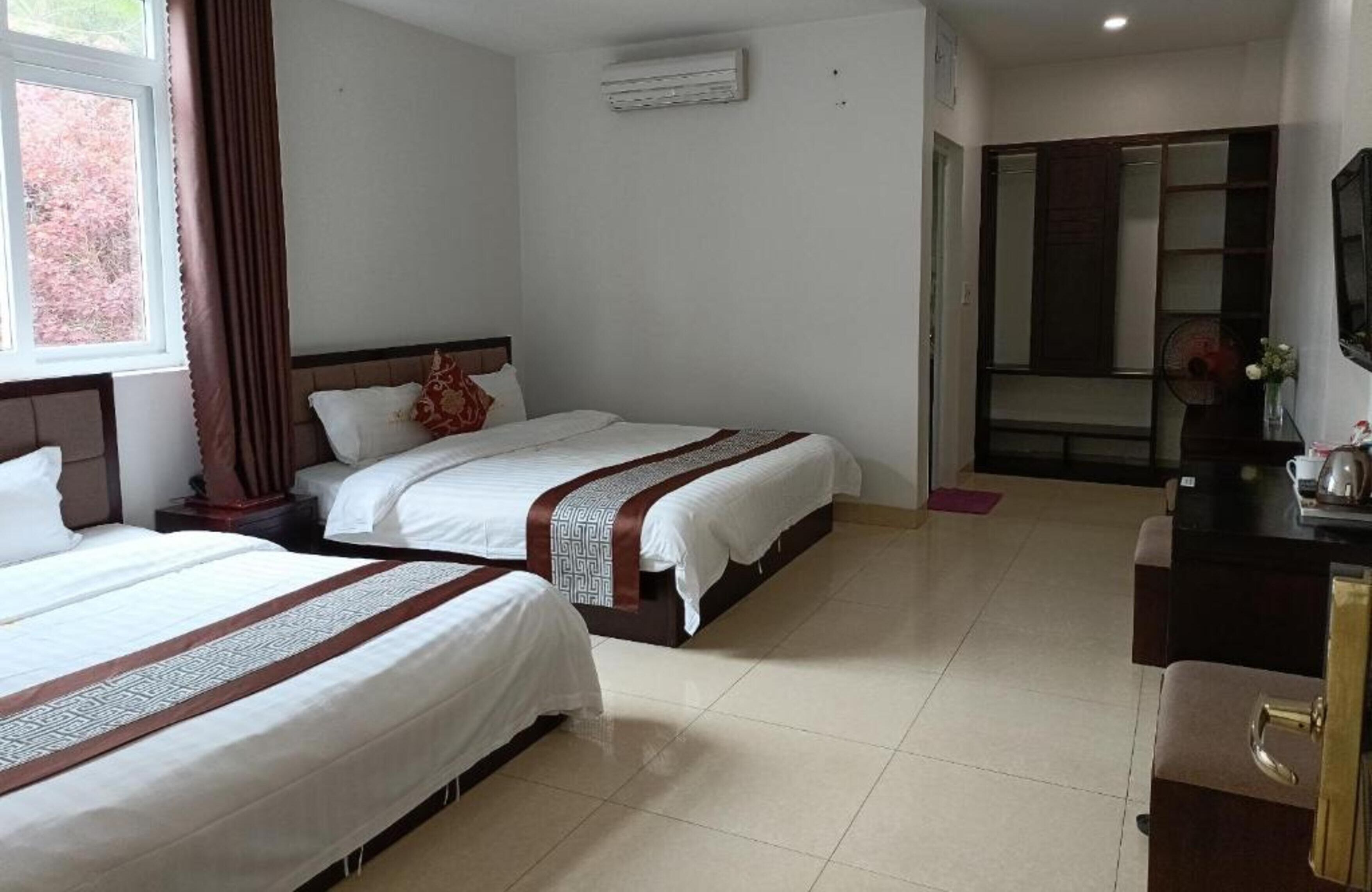 A hotel room with two beds, a desk, and a mirror.