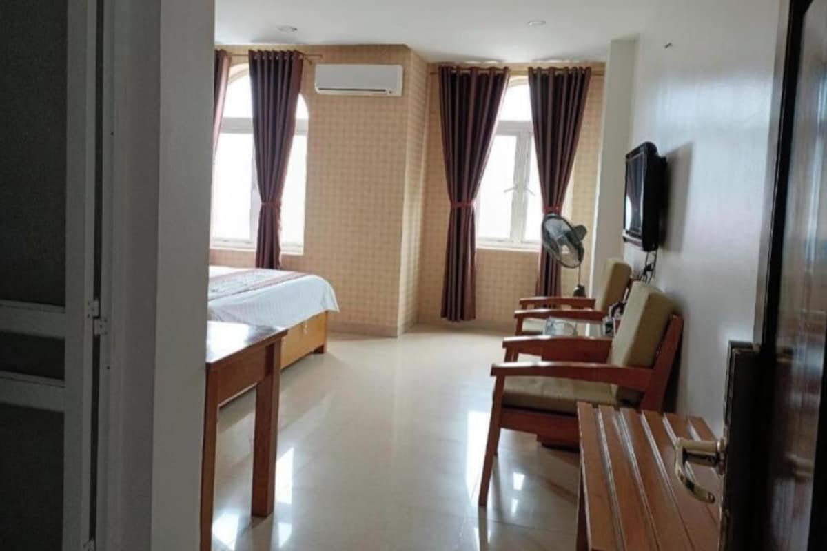 A hotel room with a bed, a desk, a chair, a television, and curtains.
