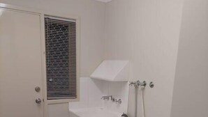 A laundry room with two washing machines, a sink, and a door with a window.