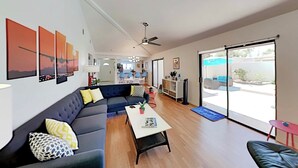 Una sala moderna con un sofá azul oscuro, una mesa de centro blanca y un amplio ventanal corredizo que da a un espacio exterior.