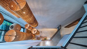 A modern interior with a staircase, wicker hanging lamps, and a view of greenery outside.