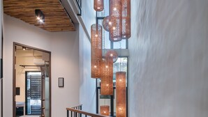 A spacious interior with a wooden ceiling, a modern staircase, and hanging pendant lights.