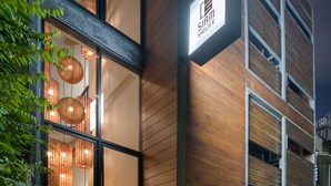 A modern building with a wooden facade, a sign reading "Siam Shelter," and a potted plant outside.