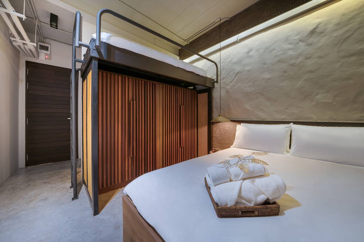 Een moderne hotelkamer met een bed, een houten garderobe en een zithoekje.
