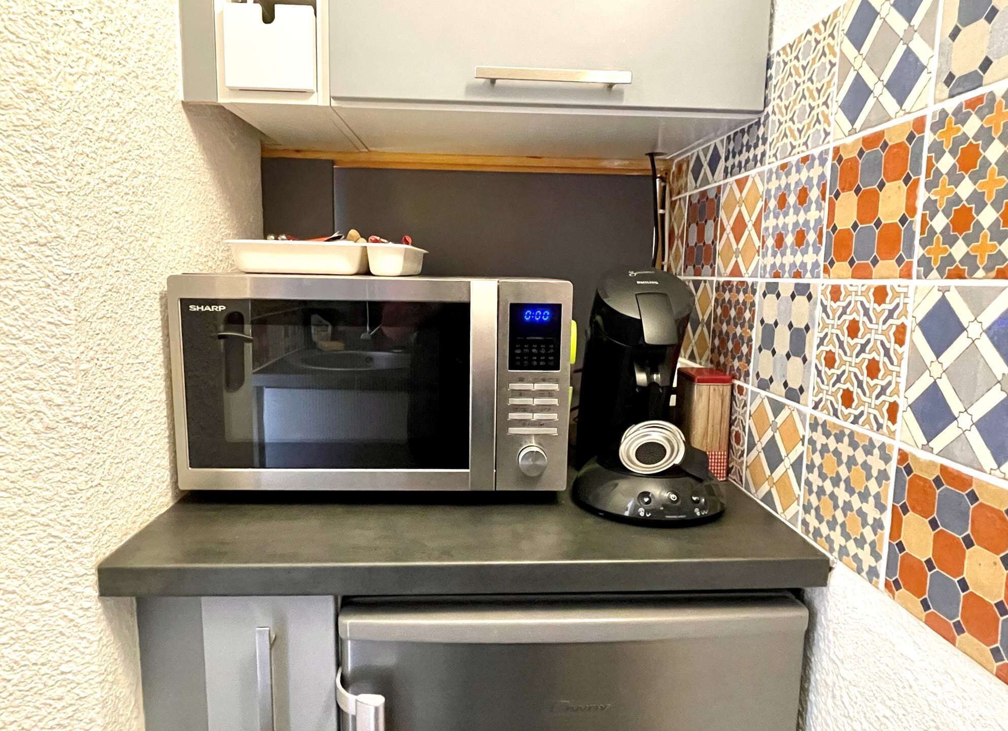 A kitchen with a microwave, coffee maker, and a small refrigerator.