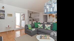 A modern living room with a grey sectional sofa, green and white patterned cushions, a small white side table, and a round coffee table with wooden letters and a small plant. - Villa Vela Private Pool Playa Blanca Pool Playa Blanca (Playa Blanca)
