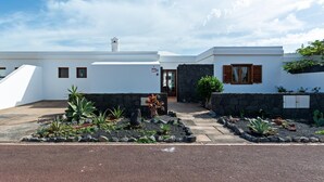 A modern house with a white exterior, a stone wall, and a paved driveway. - Villa Vela Private Pool Playa Blanca Pool Playa Blanca (Playa Blanca)
