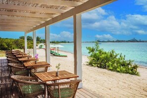 An outdoor seating area with tables and chairs, overlooking a beach and the sea. - VILLA MIRTO IS PART OF THE MOLAS RESORT (Pula)