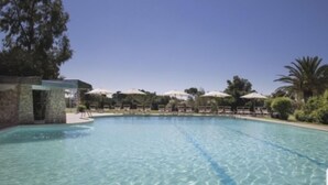 A clear swimming pool with lounge chairs and umbrellas, surrounded by greenery and a stone structure. - VILLA MIRTO IS MOLAS RESORT (Pula)