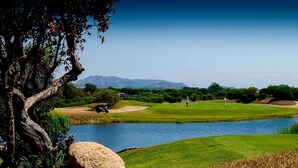 A golf course with a lake, trees, and distant mountains. - VILLA MIRTO IS MOLAS RESORT (Pula)