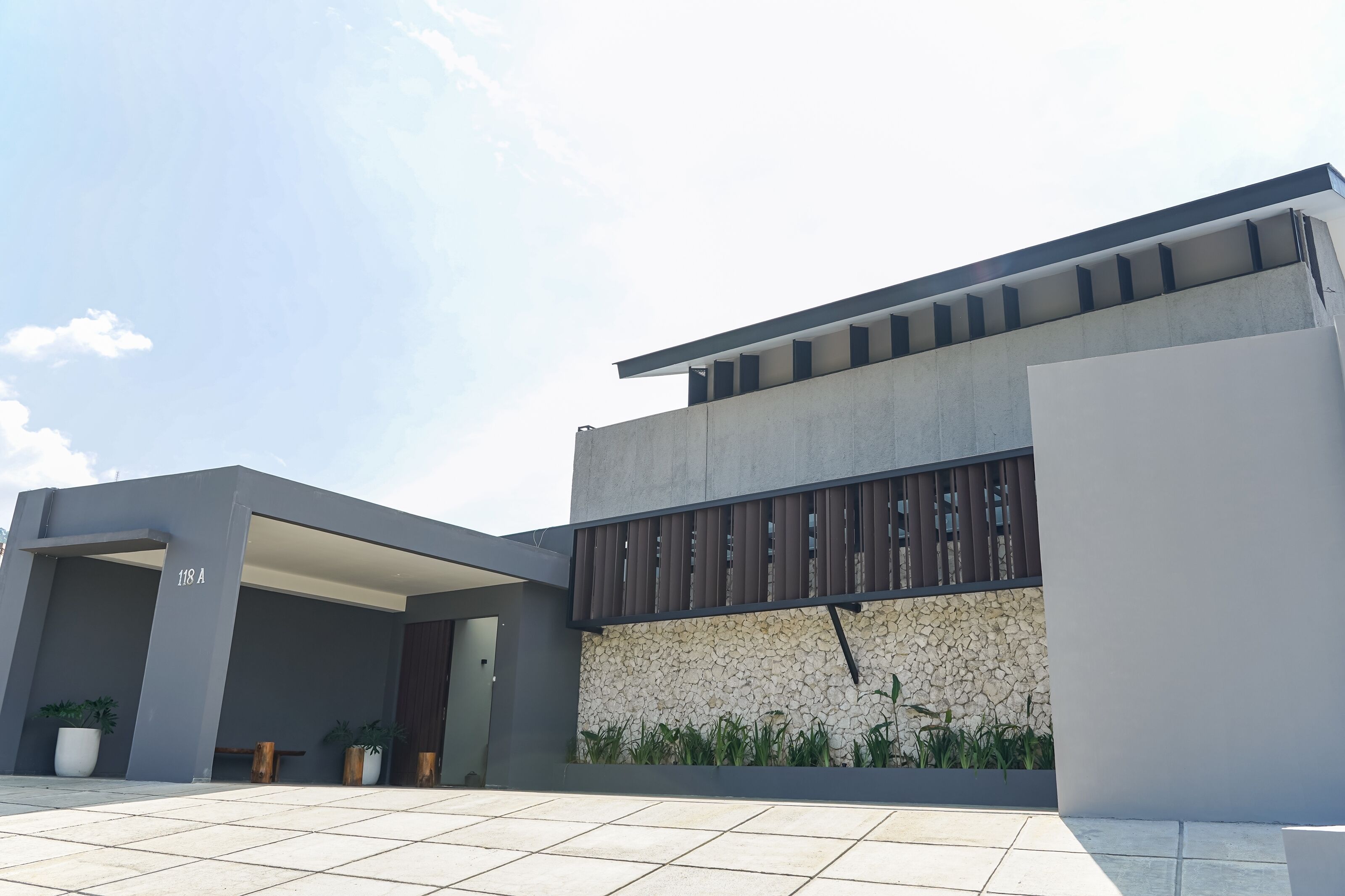 A modern building with a flat roof, a stone wall, and a tiled entrance area.