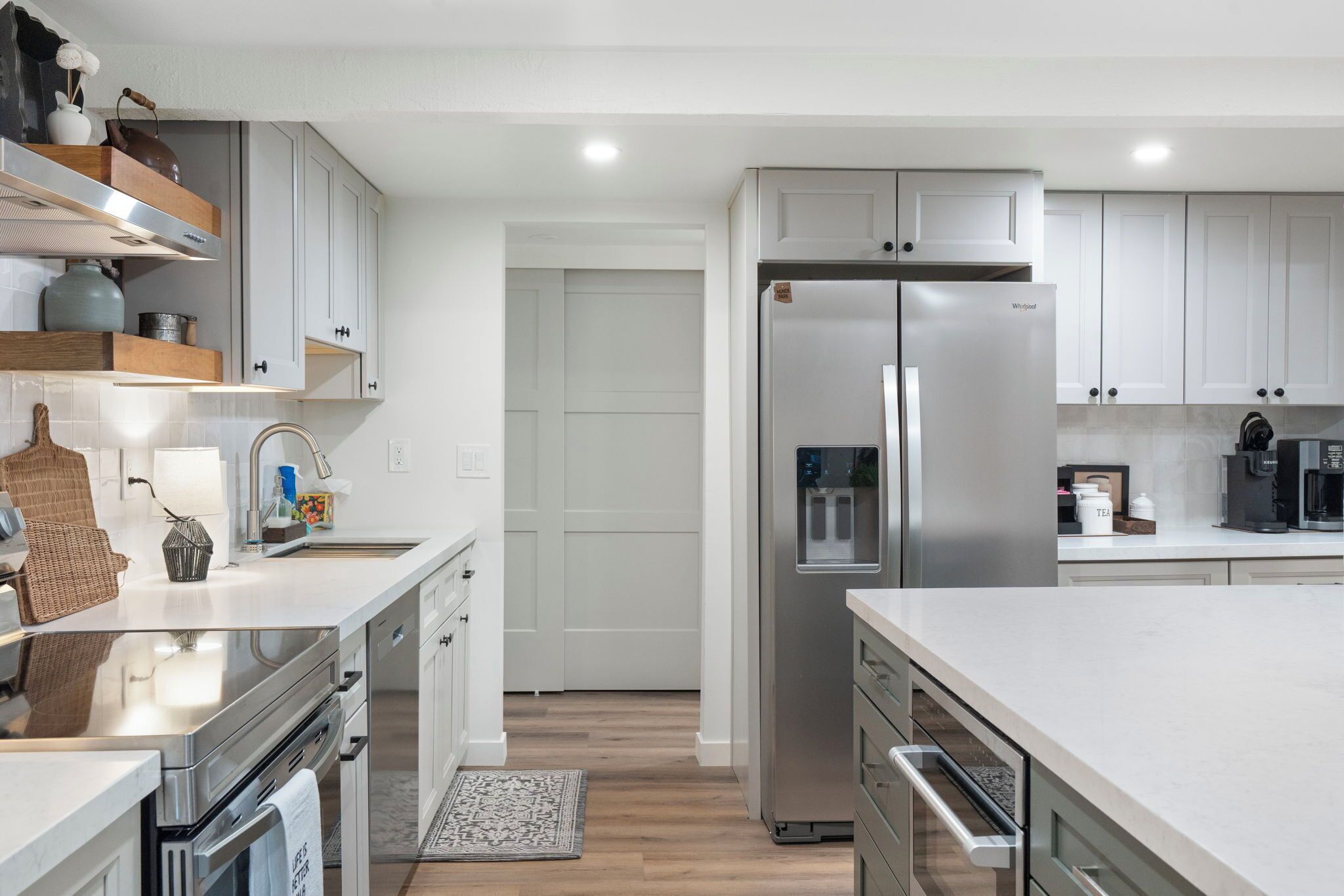 A modern kitchen with white cabinetry, stainless steel appliances, and a large island.