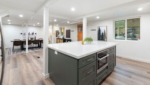 Une cuisine moderne dotée d’un grand îlot central, de planchers en bois et de murs blancs.