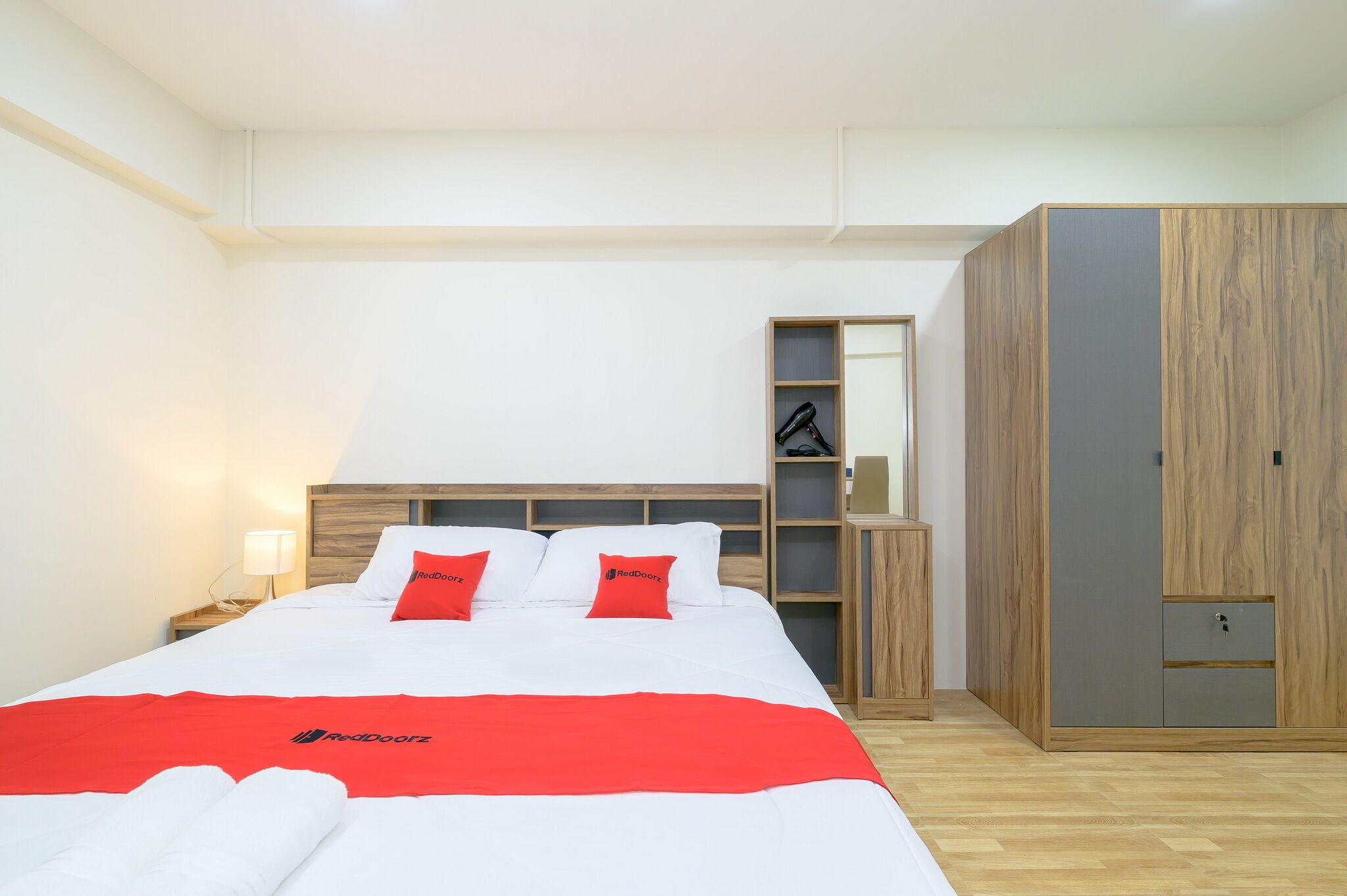 A hotel room with a bed, a wardrobe, a nightstand, and a mirror.