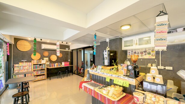 Een moderne café met een toonbank vol gebak en een boekenplank met boeken.