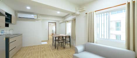A modern apartment with a kitchen, dining area, and a living room with a sofa and large window.
