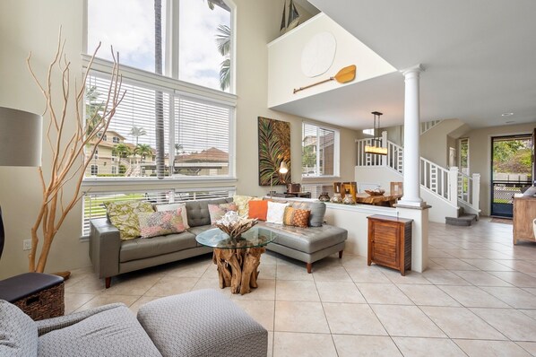 A spacious living area with a large window, a staircase, and a dining area.
