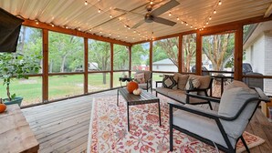 A covered patio with a wooden deck, a sofa set, a coffee table, and a ceiling fan.