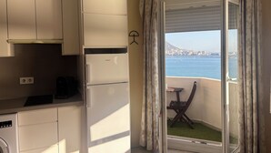 A kitchen with a refrigerator, a dining area with a table and chairs, and a balcony with a view of the sea. - Studio with terrace and spectacular views (La Línea de la Concepción)