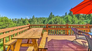 A wooden deck with picnic tables and a wicker chair, overlooking a forested area. - Charming Alto Hideaway < 14 Mi to Ski Apache! (Alto)