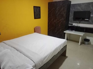Simple, functional room with a single bed, flat-screen TV, and desk.
