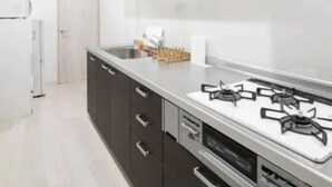 Een moderne keuken met donkere kastjes, een wit aanrecht en een gasfornuis.