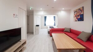Een moderne woonkamer met een flatscreen televisie, een rode bank, een houten salontafel en een schilderij aan de muur.