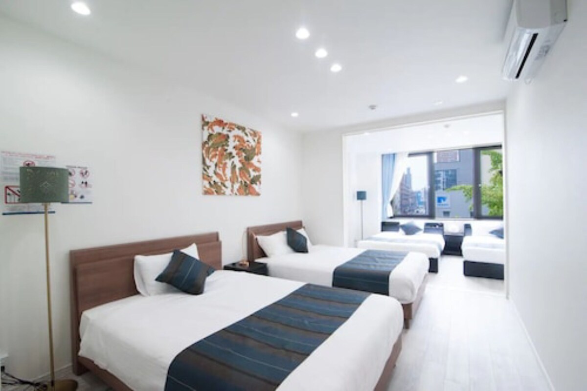 Habitación de hotel con dos camas, un ventanal grande y vista a la ciudad.