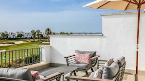 Un balcon avec des meubles d’extérieur, une vue sur un terrain de golf et un mur blanc.