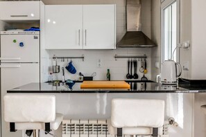 A modern kitchen with white cabinets, a stainless steel range hood, and a black countertop. - Stunning 3 bedroom townhouse - CE51LT (Torre-Pacheco)