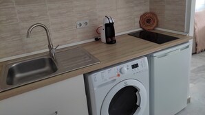 A compact kitchen with a stainless steel sink, a microwave, a coffee maker, and a washing machine. - Loft con Espectaculares Vistas al Mar, Gibraltar, Marruecos y Bahía de Algeciras (La Línea de la Concepción)