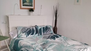 A bedroom with a bed, a chair, a bedside table, a wall-mounted picture, and a tall vase. - Loft con Espectaculares Vistas al Mar, Gibraltar, Marruecos y Bahía de Algeciras (La Línea de la Concepción)