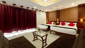 A hotel room with two beds, a glass coffee table, and a view of the city. - Hotel Burooj (Kanayannur)