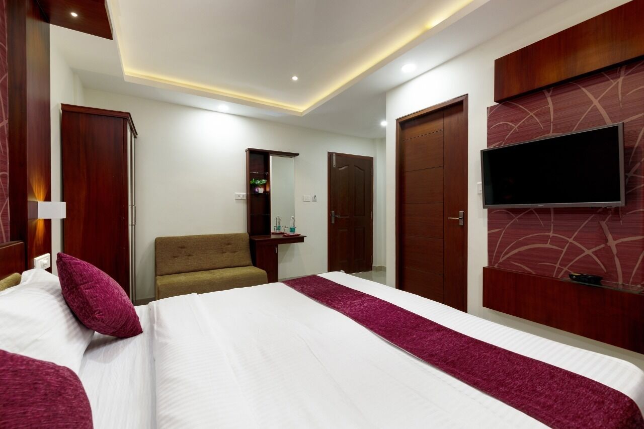 A hotel room with a large bed, a TV mounted on the wall, a wardrobe, and a mirror.