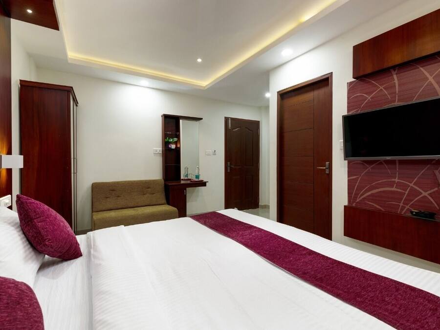 A hotel room with a large bed, a TV mounted on the wall, a wardrobe, and a mirror.