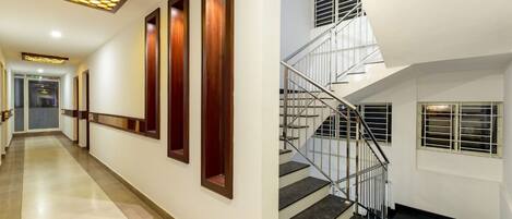 A hotel corridor with a modern staircase and a view of the interior.