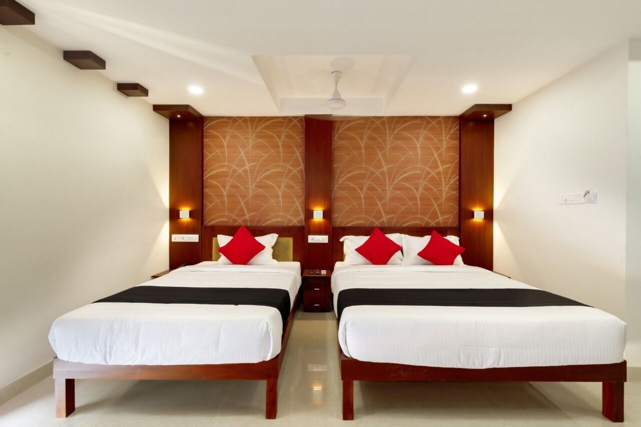Une chambre d’hôtel avec deux lits, une tête de lit en bois et un mur décoré d’un motif.