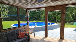 A covered outdoor deck with a pool, a sofa, and a table. - Jacksonville Ranch with private Hottub and Pool, stocked Pond with row boat, Bike and Hiking trails (Maysville)