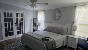 A bedroom with a bed, bedside tables, a ceiling fan, a window with curtains, and a patterned rug. - Jacksonville Ranch with private Hottub and Pool, stocked Pond with row boat, Bike and Hiking trails (Maysville)